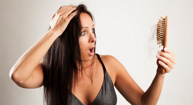 Frau blickt schockiert auf ihre Haarbürste