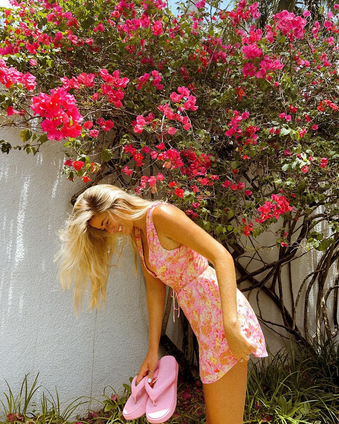 La influencer Taylor Bond con un look veraniego al lado de un árbol lleno de flores primaverales