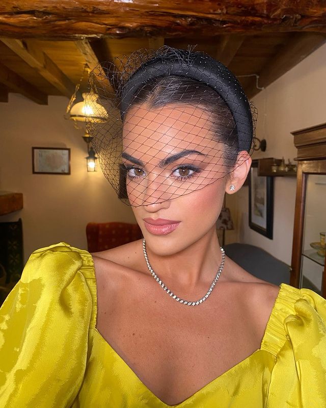 La influencer Marta Lozano con un tocado negro y un top amarillo en una boda