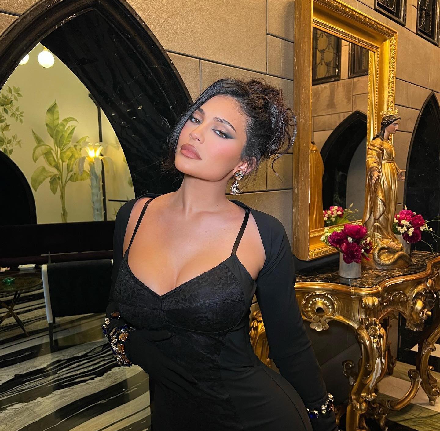 Kylie Jenner con un vestido negro de tirantes, el pelo recogido en un moño y un maquillaje en tonos nude con pouty lips