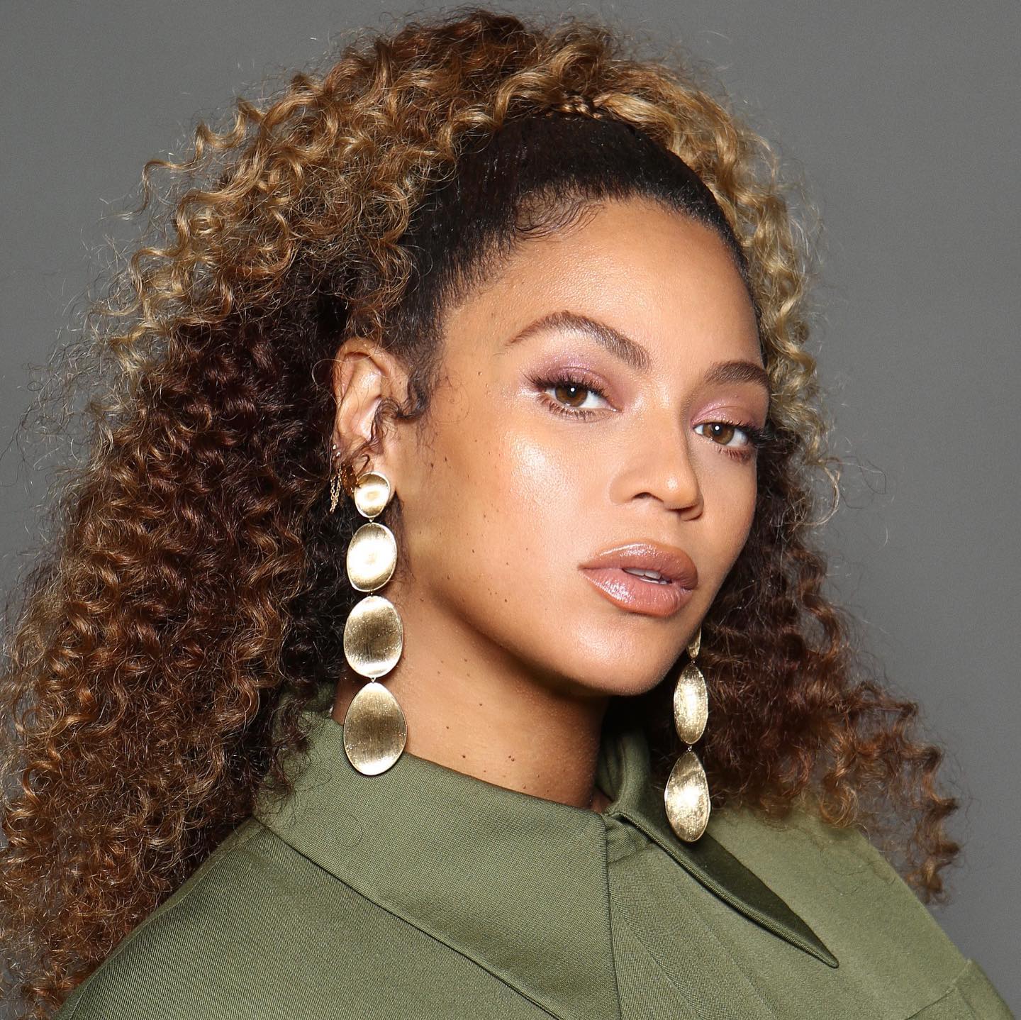 La cantante Beyoncé posa con un maquillaje en tonos nude y su característico pelo rizado recogido la mitad en un moño alto