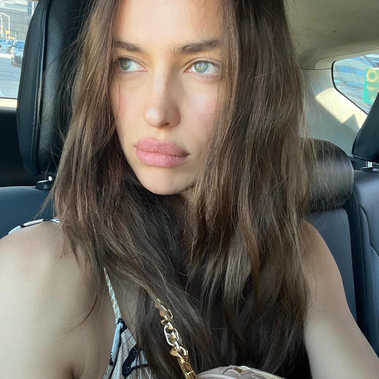 Irina Shayk en en un coche mirando hacia un lado sin maquillaje