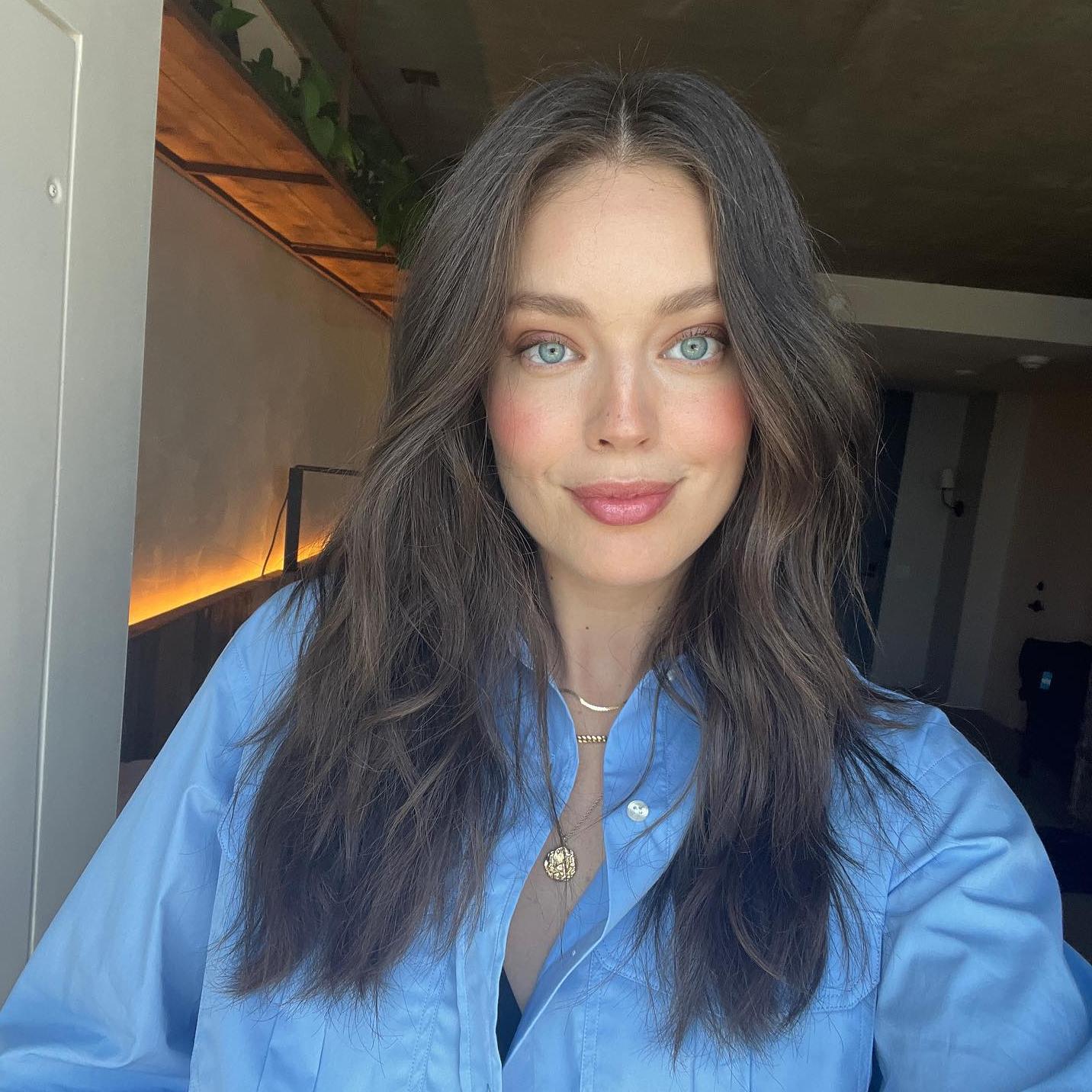 La modelo Emily DiDonato posa en un selfie con un maquillaje natural y las mejillas ligeramente marcadas. Luce el pelo suelo con melena midi ligeramente ondulada para darle volumen.