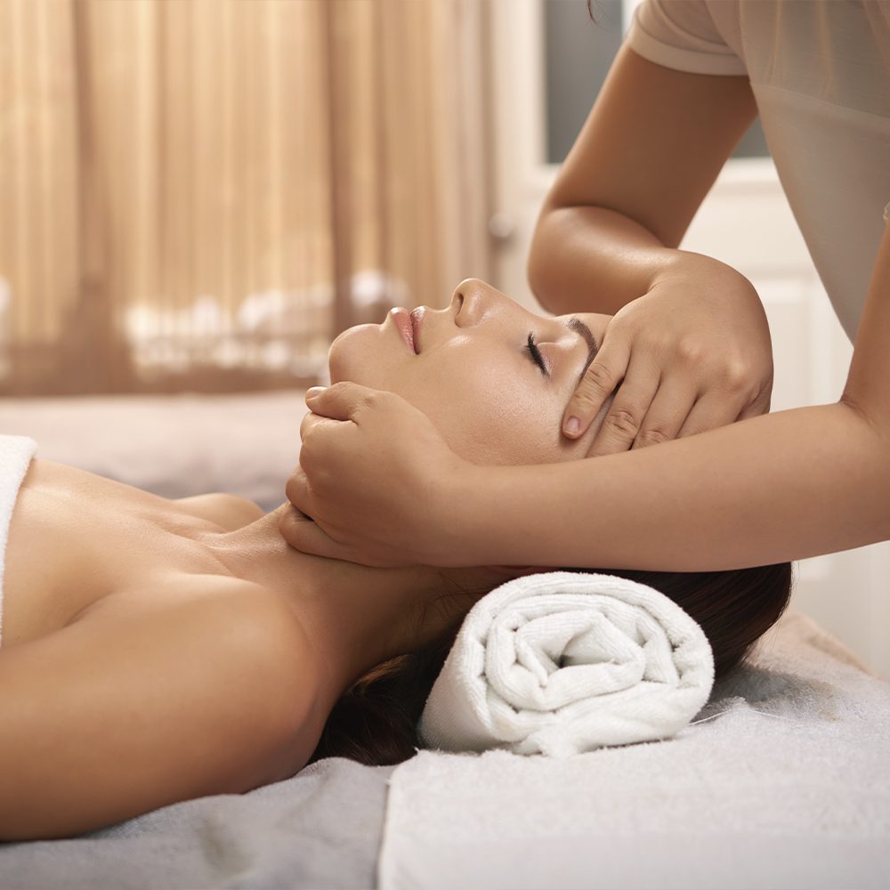 Una mujer tumbada en una camilla de masaje recibiendo un tratamiento facial