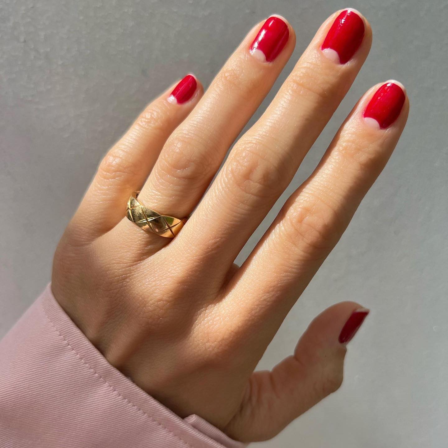 Imagen de una mano con la manicura hecha en color rojo con las semilunas sin esmalte.