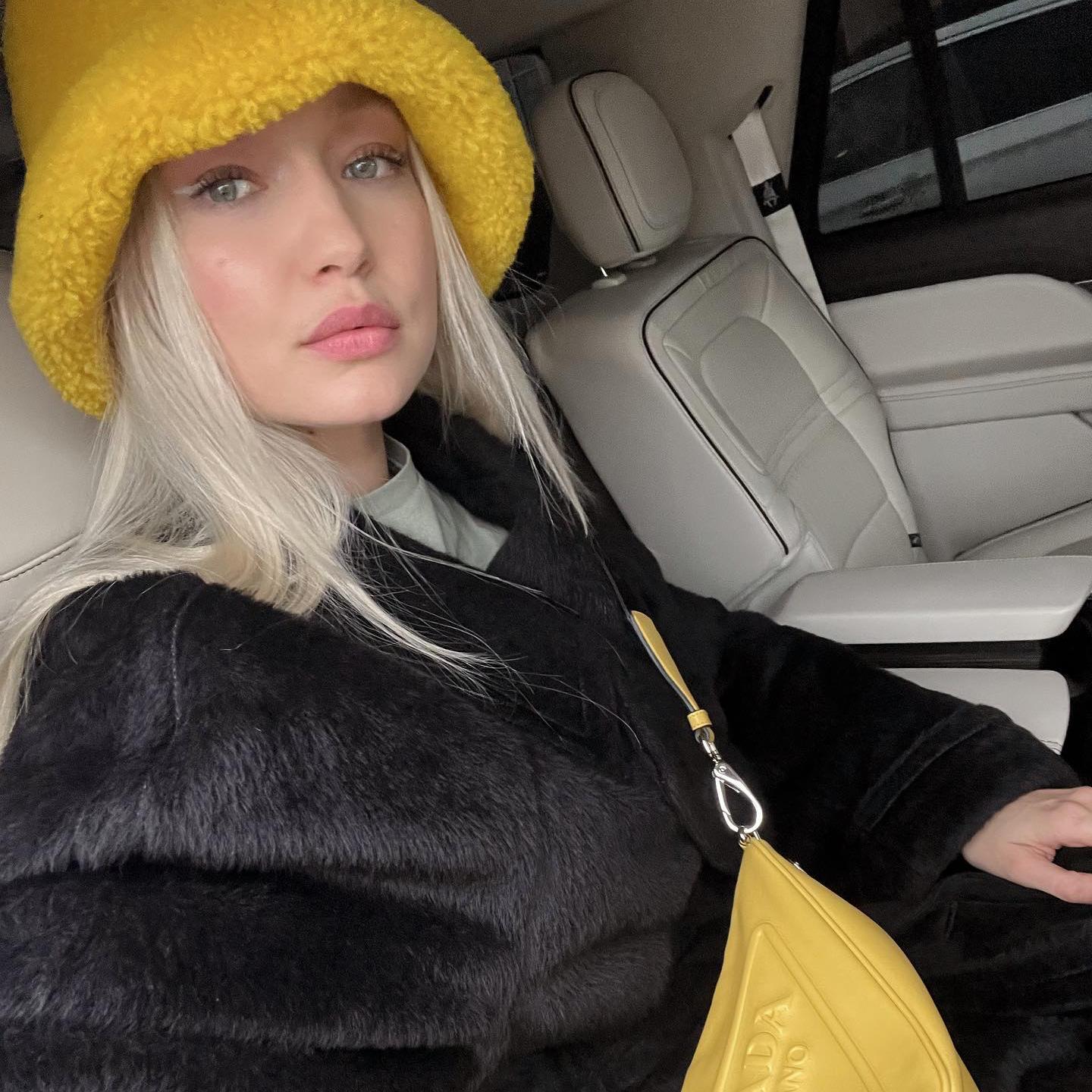 La modelo Gigi Hadid en un coche con un eyeliner blanco y accesorios furry en amarillo