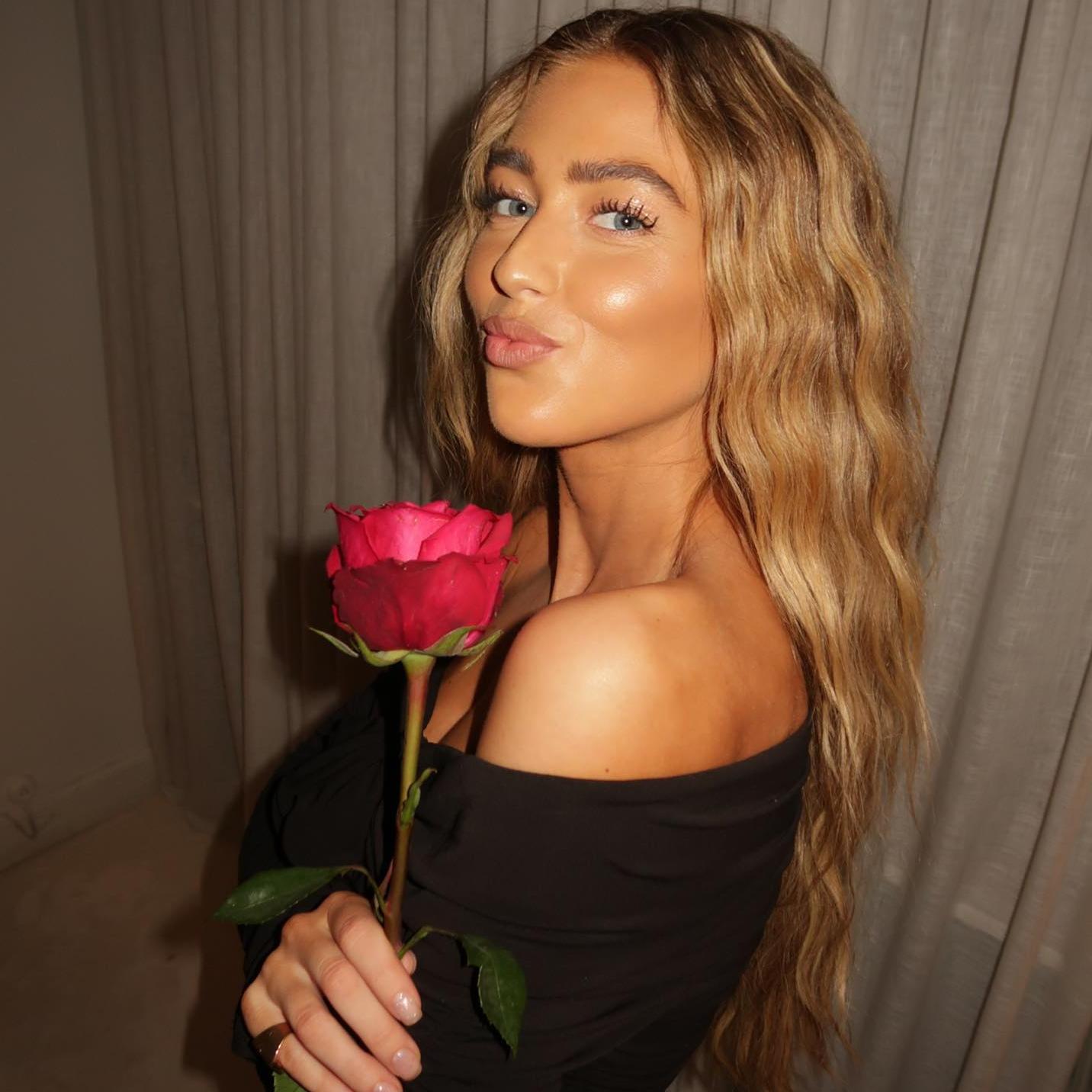 La influencer Emili Sindlev posa de perfil con una rosa en la mano, un maquillaje natural y el pelo suelo y ondulado